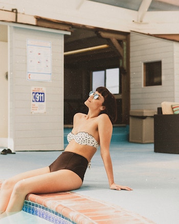 Rabatte Coupons Junge Frau sitztim Bikini am Pool | Marc O'Polo Gutschein