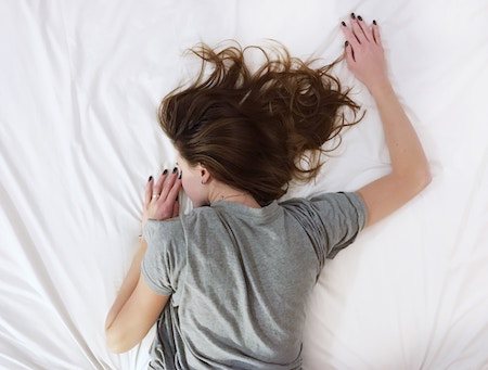 Eine Frau liegt im Bett und schläft | Rabatte Coupons