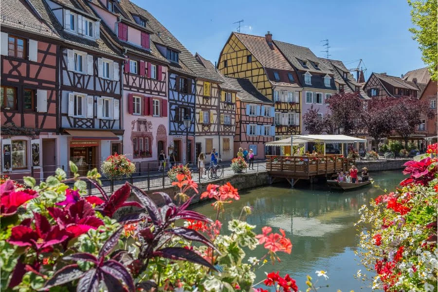 Frankreich erleben: Tolle Ziele außerhalb von Paris 3 Bunte Fachwerkhäuser und Blumen entlang eines Kanals in Colmar im Elsass.
