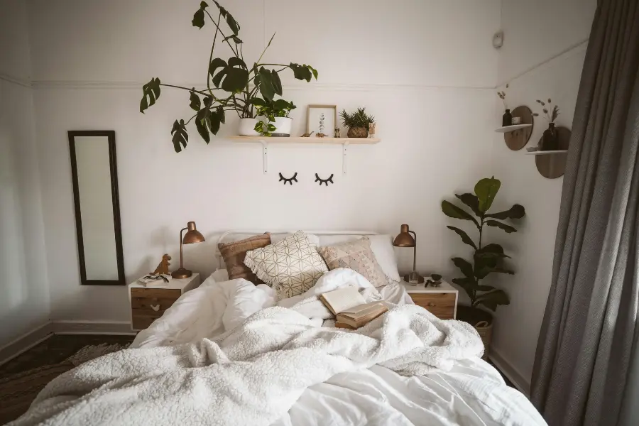 Herbst ist Kuschelzeit - mit dieser Bettwäsche wird's gemütlich 1 Gemütliches Schlafzimmer mit heller Bettwäsche, weicher Kuscheldecke, vielen Kissen, Büchern und grünen Zimmerpflanzen.