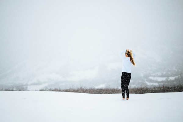 Frau steht mit Sportsachen im Schnee