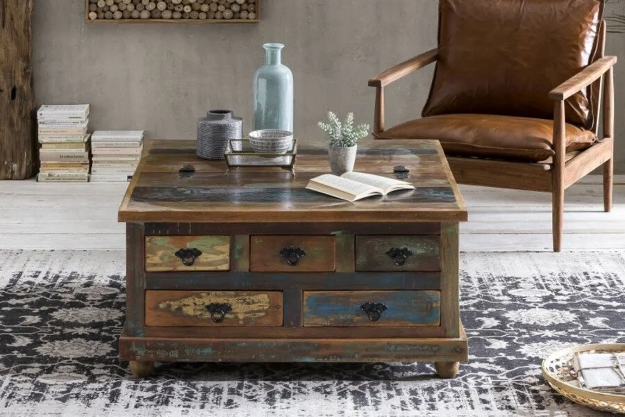 Altholz Truhe im Vintage-Stil als Couchtisch in einem Wohnzimmer mit Lederstuhl, Teppich und dekorativen Accessoires.