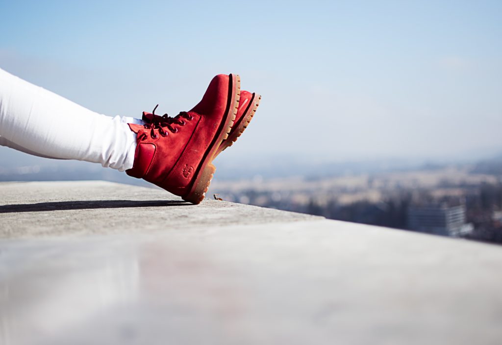 Person trägt rote Stiefel und sitzt auf einem Gebäude | rabatte coupons