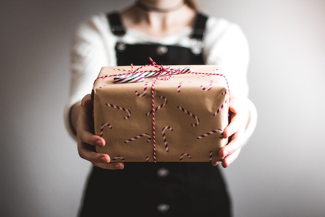 Eine Frau überreicht ein Weihnachtsgeschenk | rabatte coupons