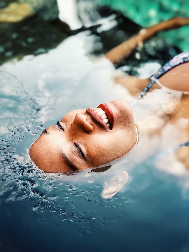 Eine Frau treibt lächelnd im blauen Wasser | parfumdreams gutschein bestandskunden