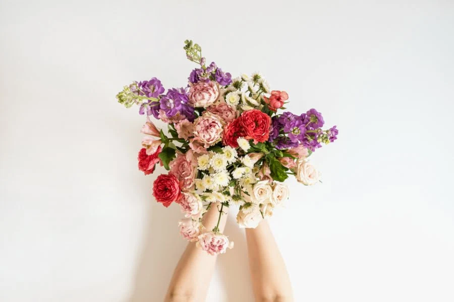 Bunter Blumenstrauß zum Muttertag wird mit beiden Händen gehalten