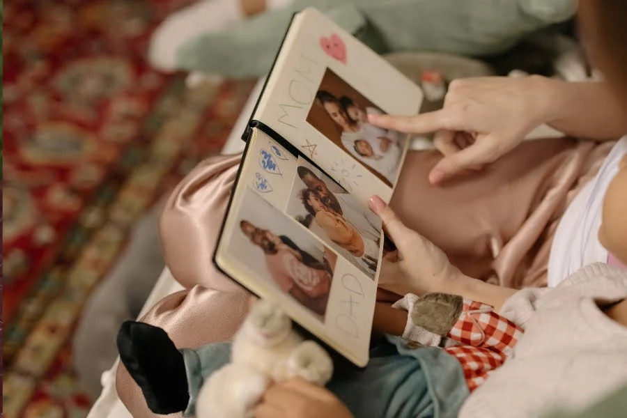 Frau schaut sich ein Fotobuch mit Familienbildern als Muttertagsgeschenk an