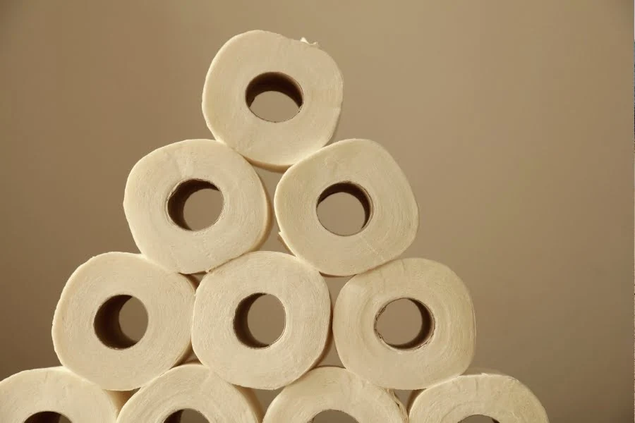 Zero Waste im Alltag - 5 einfache Tipps für's Badezimmer 1 Mehrere Toilettenpapierrollen sind pyramidenförmig gestapelt und stehen vor einem beigen Hintergrund.