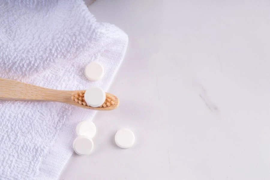Zero Waste im Alltag - 5 einfache Tipps für's Badezimmer 2 Zahnputztabletten liegen neben einer Bambuszahnbürste auf einem weißen Handtuch.