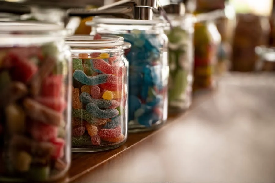Gesundheitsrisiko Zucker 🐼 Ist die Zuckersteuer Debatte legitim? 4 Verschiedene Süßigkeiten in Gläsern als Beispiel für zuckerreiche Lebensmittel