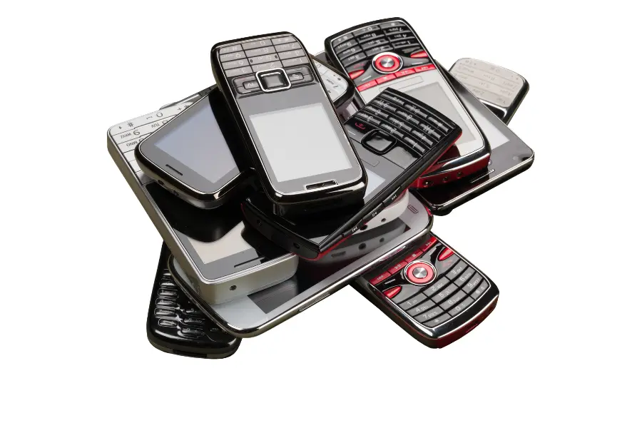 Pile of old mobile phones with keypads and small screens isolated on a white background.