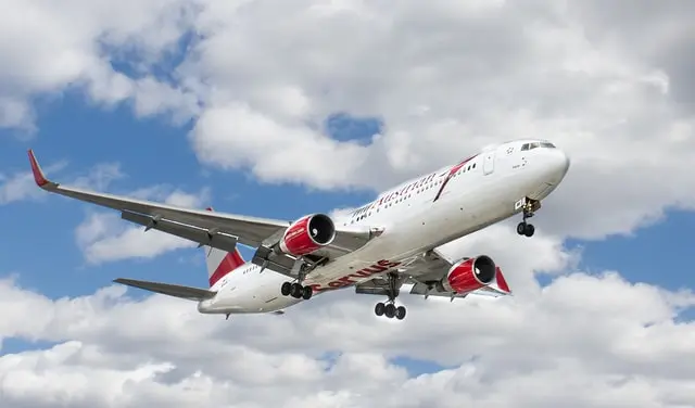 Passagierflugzeug mit rotem Triebwerk im Landeanflug vor bewölktem Himmel