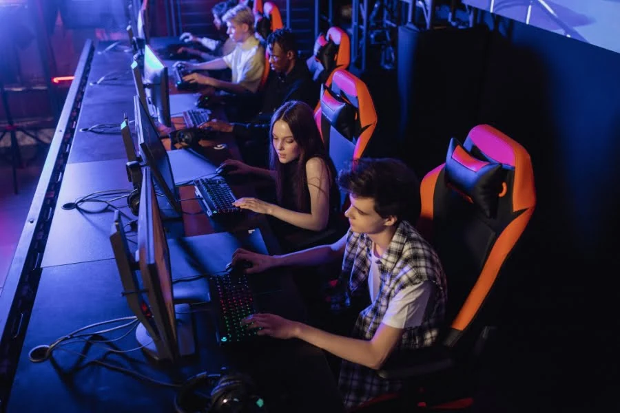 E-Sport: Wie Gaming zum professionellen Sport wurde 3 Mehrere E-Sport-Spieler sitzen an Gaming-PCs und spielen gemeinsam an einer Reihe von Computern
