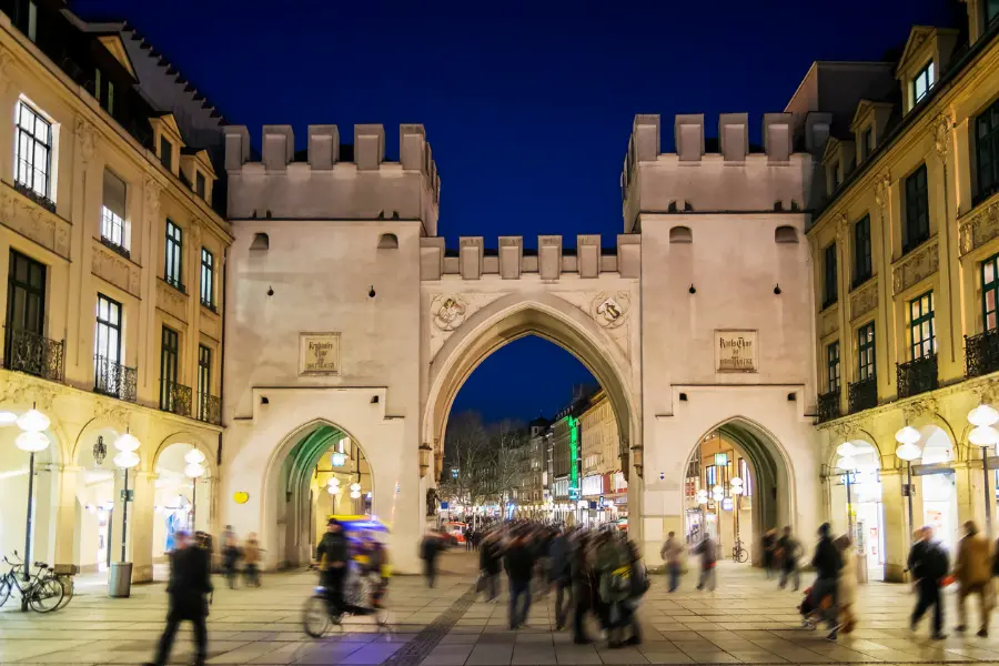 Münchens unbekannte Geschichte: Diese 3 Plätze haben Geheimnisse 3 Beleuchtetes Siegestor in München bei Abenddämmerung mit historischen Gebäuden und Lichtspuren des Straßenverkehrs.