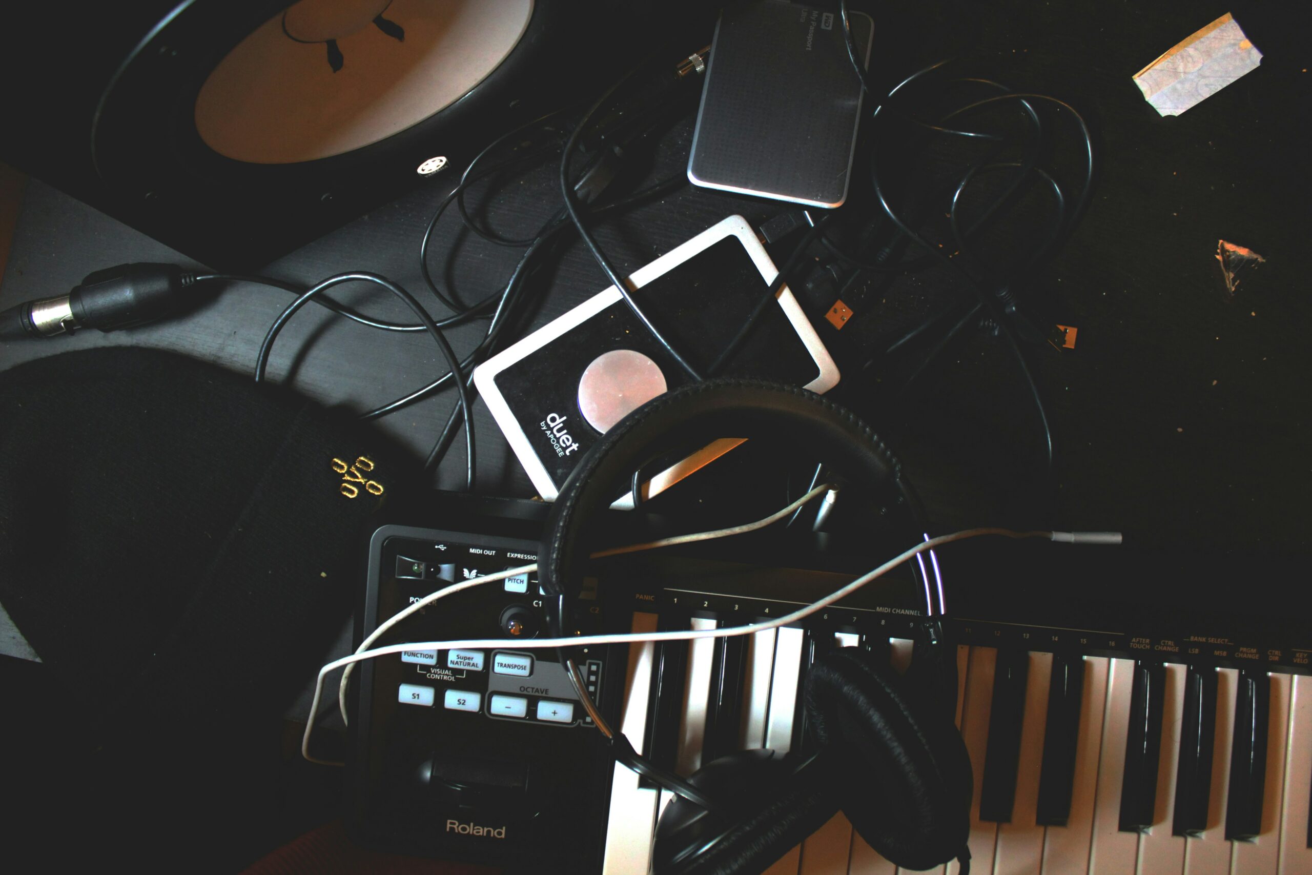 Ein Tisch mit Kopfhörer, Kabel und Instrumenten und einem Piano