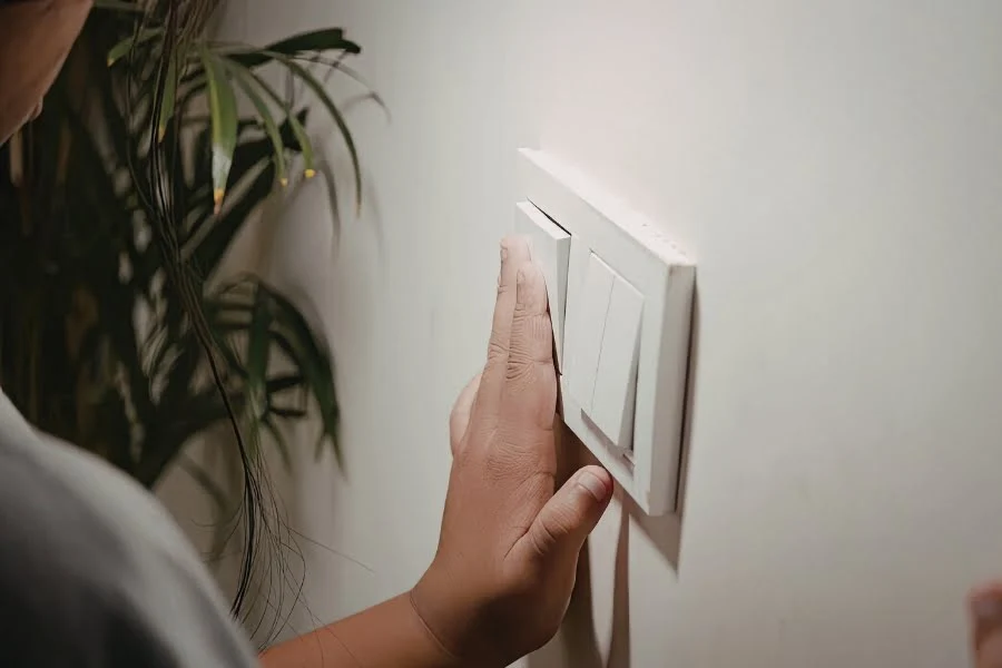 Energie sparen im Alltag: Diese Maßnahmen helfen jetzt wirklich 2 Hand schaltet Lichtschalter an einer Wand aus als Symbol für Strom sparen im Haushalt bei steigenden Energiepreisen